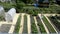 The woman has watered the seedlings planted in the garden beds and calls the cat to follow her. The view from the top. Greenhouses