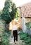 Woman in a hat with a bouquet of lavender in her hand walks along the narrow street of the old town