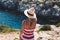 Woman in hat delighting in mediterranean scenery back view