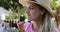 Woman in a hat eats pink ice cream in a cone on vacation.