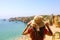 Woman with hat facing stunning view at Lagos beach in Southern Portugal