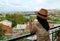 Woman in hat holding a cup of coffee while enjoy the aerial view of Tbilisi, the capital of Georgia