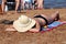 Woman in hat lies on the beach