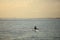 Woman in hat paddling on canoe in sunset ocean