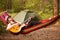 Woman in hat play guitar and relaxing in hammock in middle of forest. Slow life concept.