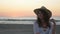 Woman with hat posing on a beach at sunrise