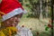 A woman in a hat of Santaclaus with a sly evil face among the autumn foliage as a harbinger of the coming winter.