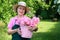 Woman in hat smiling while holding basket of roses.