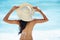 Woman, hat and travel to beach or sea, nature and relaxing by ocean for peace on vacation. Female person, outdoors and