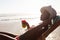 Woman having cocktail drink while relaxing in a beach chair on the beach