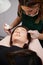 Woman having eyelash extension procedure in beauty salon.