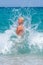 A  woman having fun in the waves of the sea which are splashing her. The beautiful woman mother of three in bikini