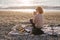 Woman having picnic at beach with tea in thermos.