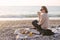 Woman having picnic at beach with tea in thermos.