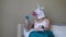 Woman with a head mask of unicorn talking to web camera on smart phone on a bedroom. Social media concept. Weird funny