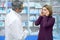 Woman with headache asking pharmacist for pills.