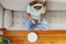 A woman in headphones sits on couch while a robotic vacuum cleaner does cleaning