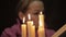 Woman in a headscarf doing the magic ritual. close-up several candle and old book. halloween or religion concept