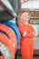 Woman in a headscarf wearing a wearpack uniform with crossed hands next to a tire rack