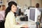 Woman With Headset Working At Desk In Busy Creative Office