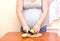 Woman and healthy food. Pregnant woman cuts green apple.