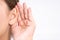 Woman hearing loss or hard of hearing and cupping her hand behind her ear isolate on white background, Deaf concept