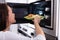 Woman Heating Fried Food In Microwave Oven