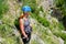 Woman with helmet and via ferrata gear looking down towards Cikola river, in Cikola canyon, Croatia, on a bright, sunny day.