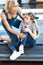 Woman helping girl injured knee sitting on treadmill