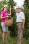 Woman helping an older man in the orchard, to pick apple