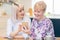 Woman Helping Senior Neighbor Explaining How To Use Mobile Phone