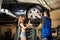 woman helps auto mechanic repair car on hydraulic lift