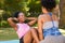 Woman helps her friend with sit up crunches, assist in park, fitness buddy