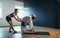 The woman helps make a man a camel pose. Yoga practice in the studio.