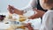 Woman with her child puts sugar in the dough for preparing pancakes