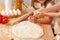 Woman with her children kneading dough in kitchen