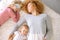 Woman and her daughter having rest on the bed while the baby has waken up