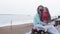 A woman with her daughter looking through binoculars on the beach