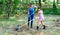 A woman and her daughter work in the garden gathering the freshly cut dry grass