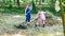 A woman and her daughter work in the garden gathering the freshly cut dry grass