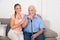 Woman With Her Disabled Father Sitting On Sofa