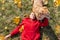 A woman and her dog are relaxing in an autumn park. They are lying on the lawn in orange leaves. Top view