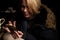 A woman in her forties sits with a phone in her hands in the dark. Attractive woman smiles and looks into a mobile phone