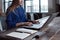 Woman with her hands on laptop keyboard. Designer sitting at worktable with notebook and computer on it.