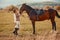 Woman with her horse at sunset, autumn outdoors scene