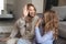 Woman with her little sister indoors at home give a high five to each other