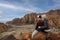 Woman and her son sitting on a rock ledge overlooking beautiful Snow Canyon State park in the deserts of Utah enjoying the view