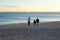 A woman with her sons in ordinary clothes while walking on the seashore on a winter sunny day