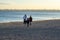 A woman with her sons in ordinary clothes while walking on the seashore on a winter sunny day