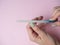 A woman herself is filing her nails with a nail file on her hand on a pink background. Hand nail care at home. Beauty and Health